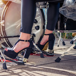 woman with high heels playing a drum set